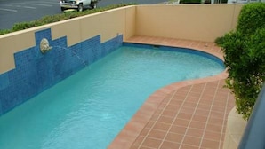 En swimmingpool med en kant och en vägg som är klädda med blå kakelplattor.