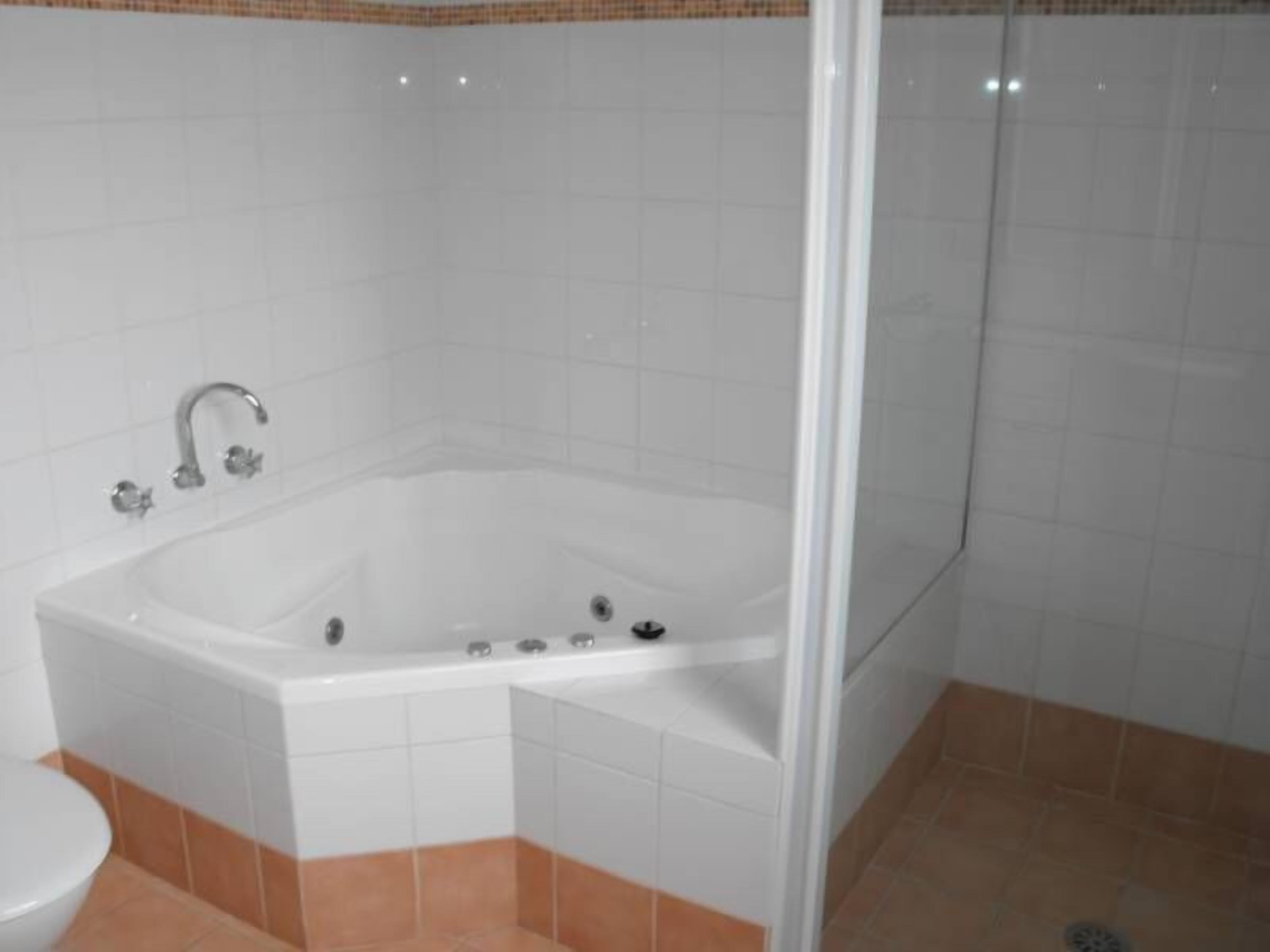 Un baño con una bañera blanca, un inodoro y una zona de ducha.