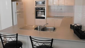 Una cocina moderna con gabinetes blancos, horno empotrado y un lavamanos doble.