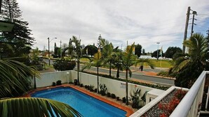 Una piscina rodeada de palmeras y una carretera al fondo.