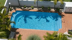 An aerial view of a swimming pool surrounded by palm trees and a brick pathway. - Mirage Unit 602 (Tuncurry)