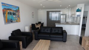 Ein modernes Wohnzimmer mit schwarzen Ledersofas, einem Holztisch und einem Essbereich mit Holztisch und Stühlen.