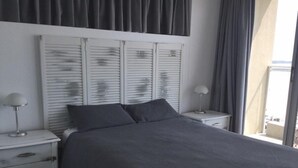 Ein Schlafzimmer mit einem großen Bett, zwei Nachttischen und einem Fenster mit Vorhängen.