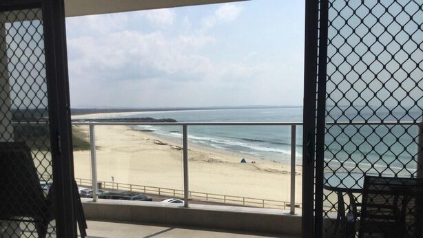 Ein Balkon mit Blick auf Strand und Meer.