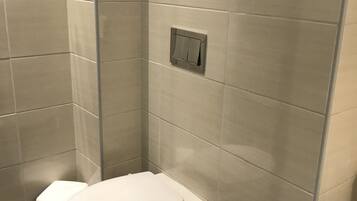 Une petite salle de bain moderne, équipée de toilettes et d’une cabine de douche.