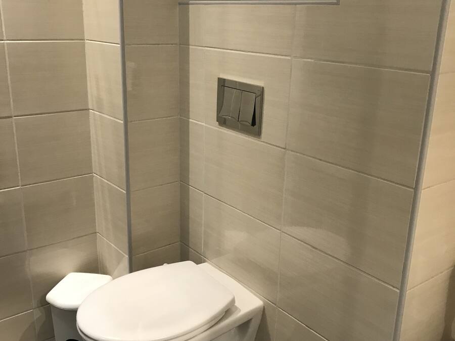Une petite salle de bain moderne, équipée de toilettes et d’une cabine de douche.