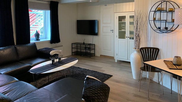 A modern living room with a sofa, coffee table, and dining area. - Notodden Sentrum Apartment No 1 (Notodden)