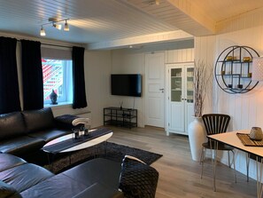 A modern living room with a sofa, coffee table, and dining area. - Notodden Sentrum Apartment No 1 (Notodden)