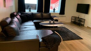 A modern living room with a sectional sofa, a small round table, and a TV on a stand. - Notodden Sentrum Apartment No 1 (Notodden)