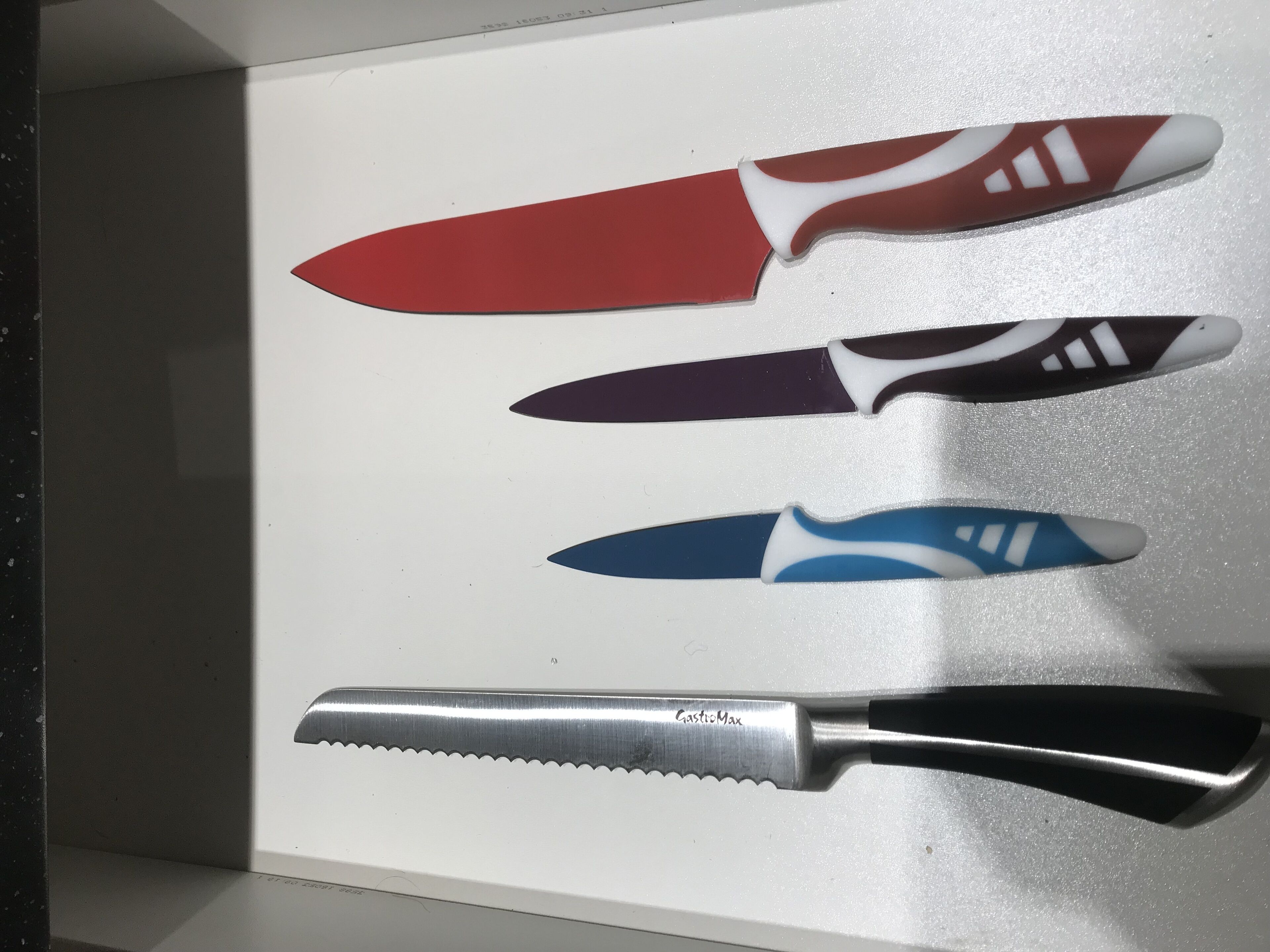 A knife with a serrated edge and a handle labeled "GastroMax" on a white surface.
