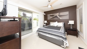 A bedroom with a bed, a ceiling fan, a nightstand, and a TV. - One Mile House (Forster)