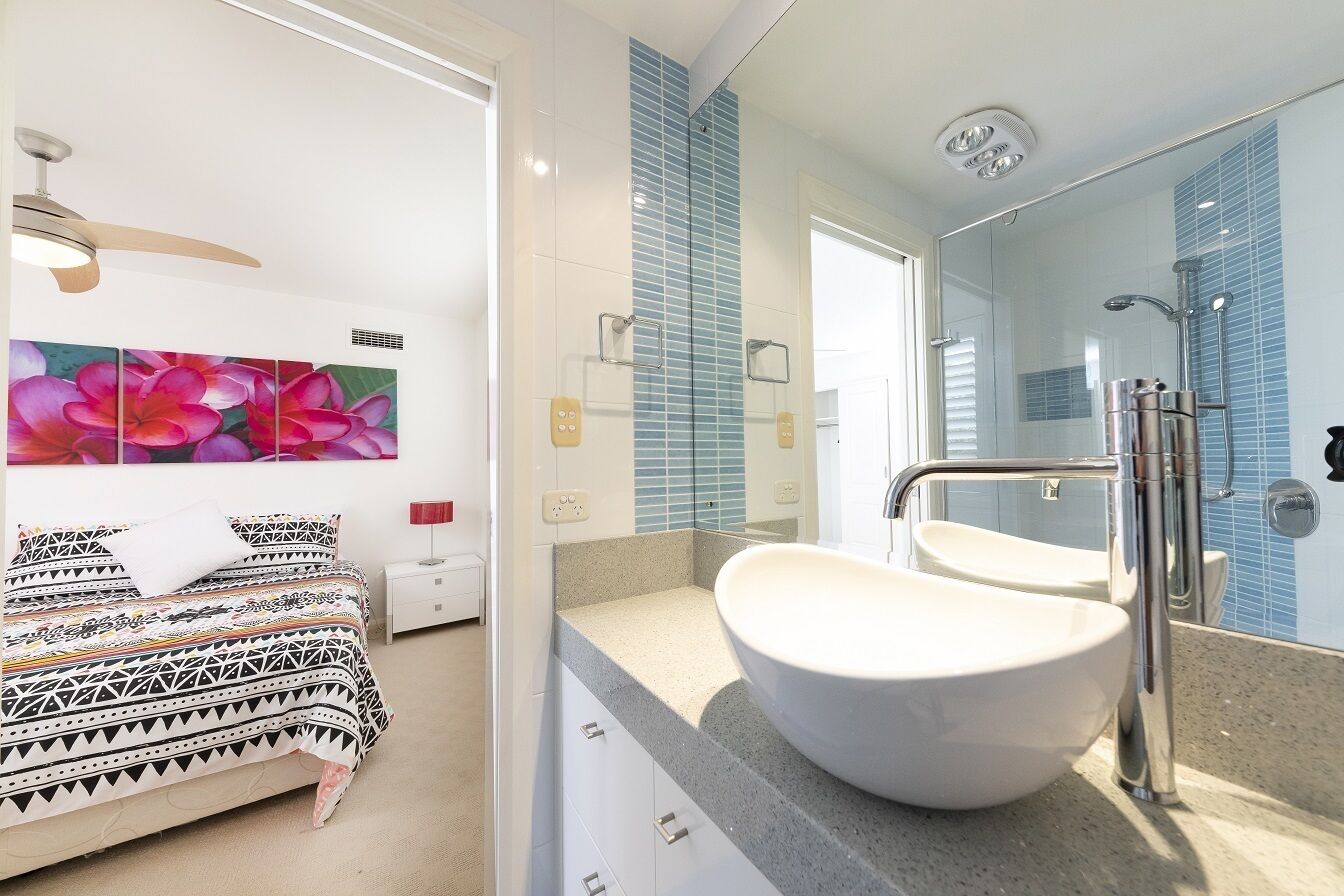 A modern bathroom with a large sink, a mirror, and a shower.