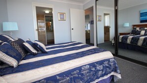A hotel room with a large bed, a mirror, and a view of the bathroom. - Pinnacle Unit 403 (Forster)