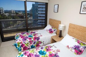 A hotel room with two beds, a large window with a city view, and a framed picture on the wall. - Pinnacle Unit 701 (Forster)