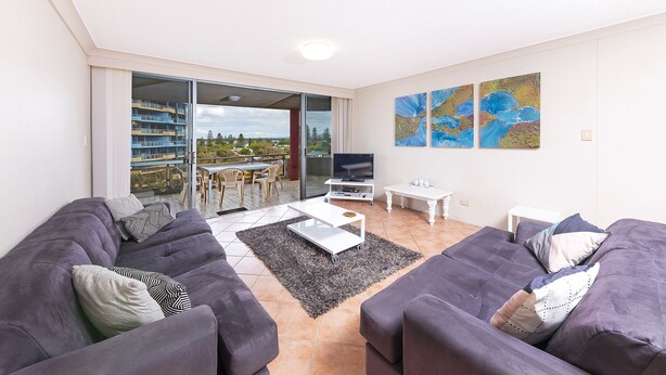 Ein modernes Wohnzimmer mit zwei Sofas, einem Couchtisch, einem Fernseher und Kunstwerken an der Wand.