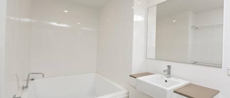 A modern bathroom with a bathtub, a sink, and a large mirror.