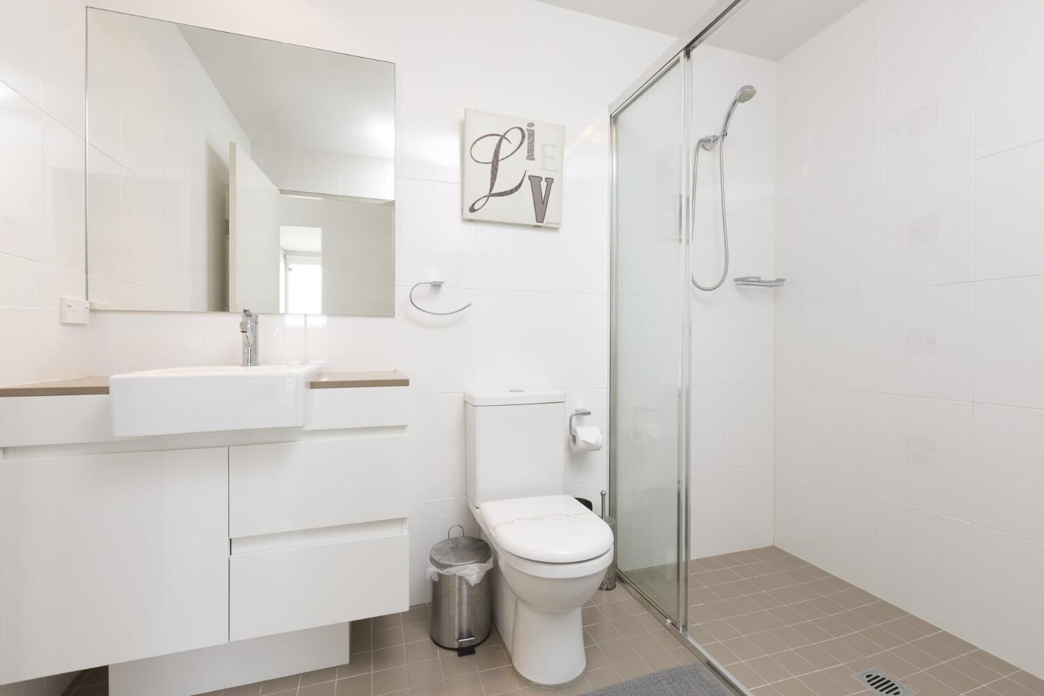 A modern bathroom with a glass shower enclosure, a white sink, and a toilet.