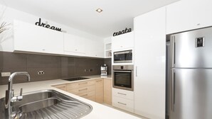 Una cocina moderna con electrodomésticos de acero inoxidable, horno integrado y refrigerador.