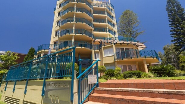 A multi-story residential building with balconies, a staircase, and a sign indicating private property. - Whitesands Unit 103 (Forster)