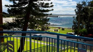 A coastal view with a bridge, grassy areas, and a road with vehicles. - Whitesands Unit 103 (Forster)