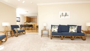 A living room with a sofa, chairs, and a dining area in the background. - Whitesands Unit 103 (Forster)