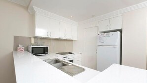 Een moderne keuken met witte kasten, een magnetron, een spoelbak en een koelkast.