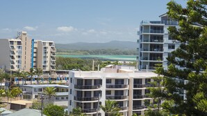 A modern hotel with multiple floors, balconies, and a view of a coastal area with mountains in the background. - Whitesands Unit 602 (Forster)