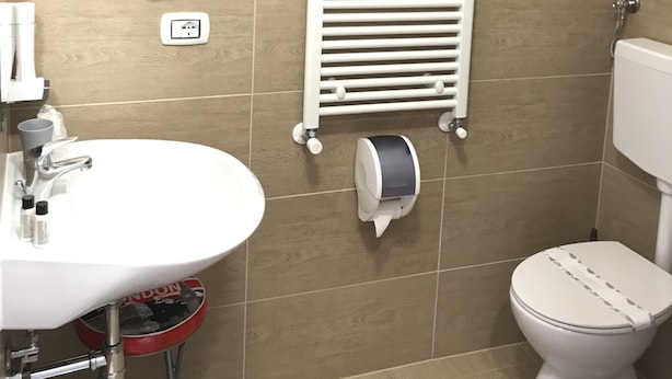 A bathroom with a white sink, toilet, and a towel rack. - Atico Hotel (Desenzano del Garda)