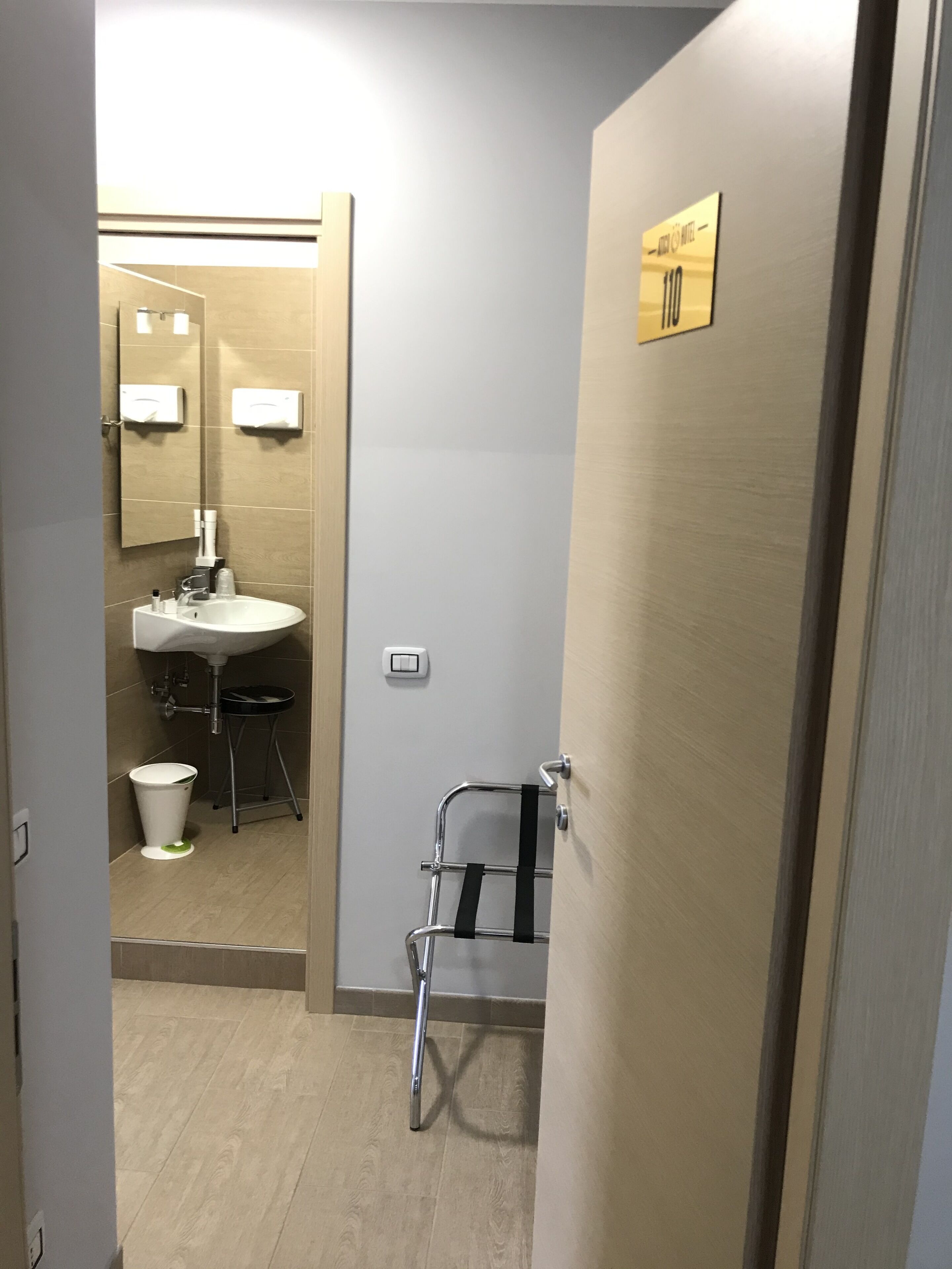 A modern bathroom with a sink, mirror, and towel rack.