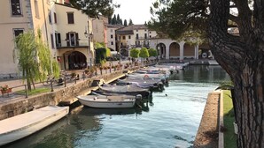 A canal lined with boats, a stone wall, and buildings with balconies. - Atico Hotel (Desenzano del Garda)