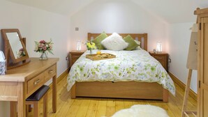 Un dormitorio con una cama de madera, una mesita de noche con lámpara, un espejo y un aparador.