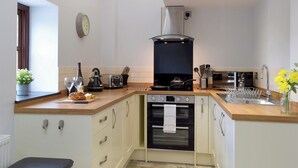 Una cocina moderna con horno empotrado, estufa a gas y pileta de acero inoxidable.