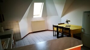A kitchen with a wooden countertop, a dining table with chairs, a radiator, and a skylight. - Peregrino Vendégház (Budaors)