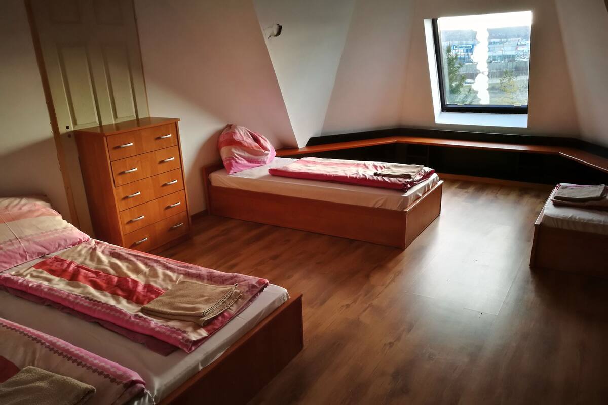 Una camera da letto con due letti, un comò in legno e una finestra vista città.