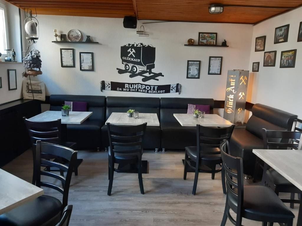 Interior de un restaurante con cabinas, mesas y sillas. Decoración en las paredes y una lámpara en el techo.