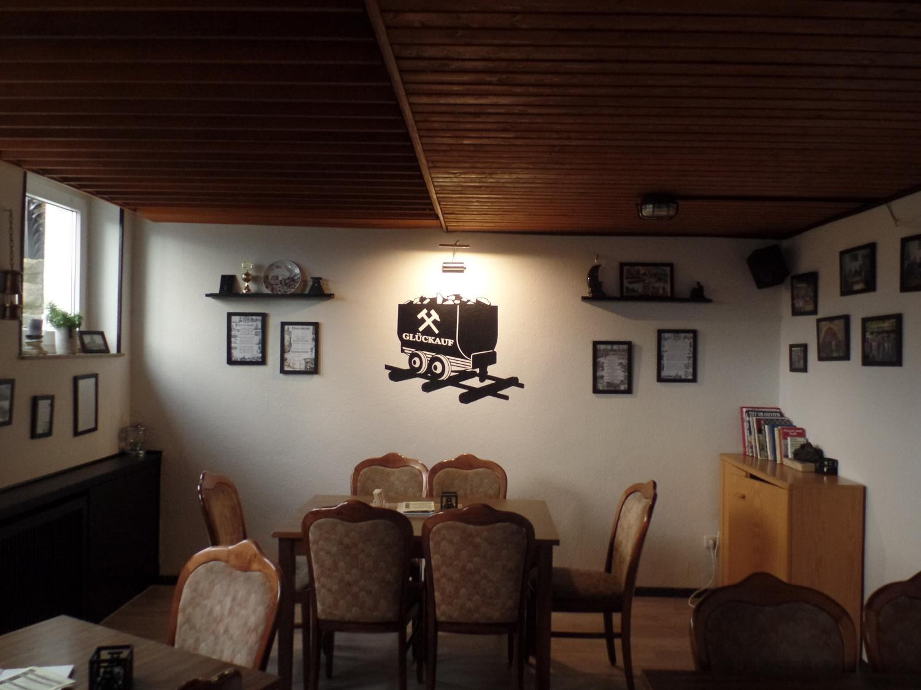 Un espace repas doté d’un plafond en bois, d’un luminaire fixé au mur et de tableaux encadrés.