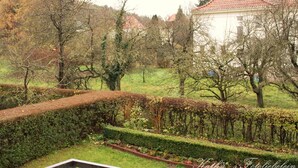 A garden with neatly trimmed hedges, a white building with a red roof, and trees in the background. - Hotel Vogt (Bad Driburg)