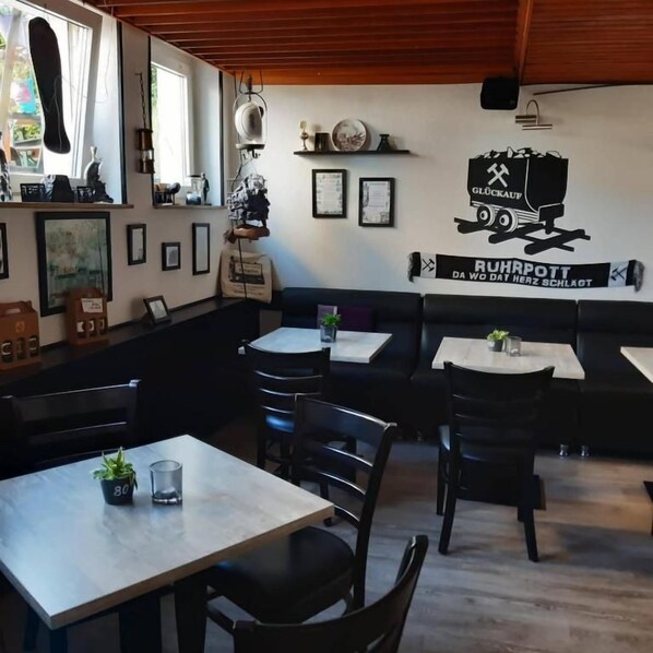 Interior de restaurante con mesas, sillas y una pared con la imagen de un camión y texto.