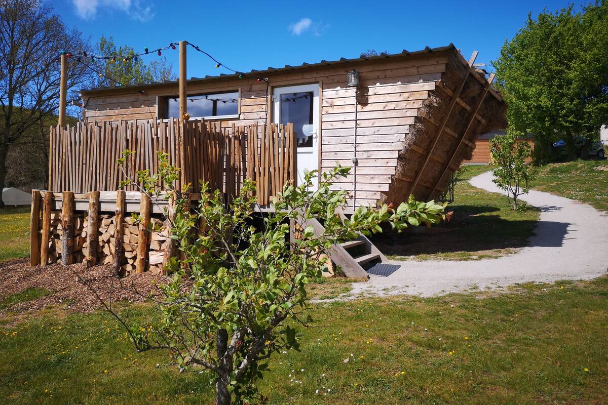 Una pequeña cabaña de madera con techo inclinado, una valla de madera y un camino que lleva a la entrada.