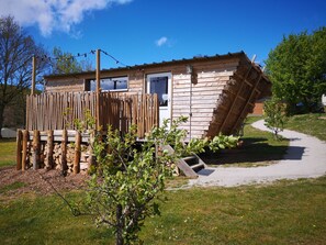 Eine kleine Holzhütte mit geneigtem Dach, einem Holzzaun und einem Weg zum Eingang.