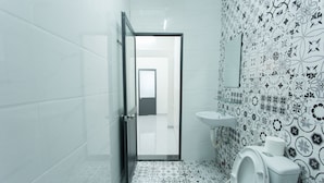 A bathroom with a patterned floor, a toilet, a sink, and a mirror on the wall. - King Homestay (Hue)