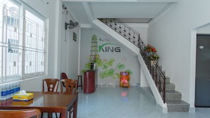 A spacious room with a dining area, a staircase, and a wall with a mural. - King Homestay (Hue)