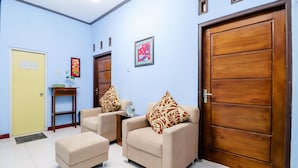 A room with two beige armchairs, a small table, and a wooden door. - Nabhan Homestay (Kalirejo)