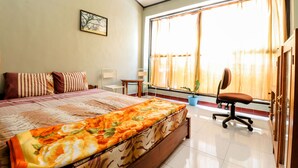 A bedroom with a large bed, a desk, a chair, and a window with curtains. - Nabhan Homestay (Kalirejo)