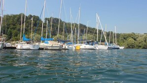 A marina with multiple sailboats docked, surrounded by greenery and trees. - A Country House near the Lake Cod. 012104-CNI-00006 IT012104C24MJ5EPRC (Monvalle)