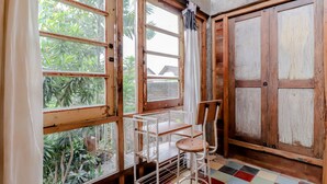 A room with large windows, a wooden chair, and a metal table. - Lorong Homestay (Kasihan)