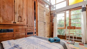 A bedroom with a bed, wooden wardrobe, and a window with a view of greenery. - Lorong Homestay (Kasihan)