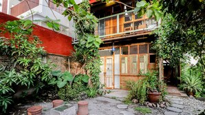 A courtyard with a stone pathway, potted plants, and a wooden balcony. - Lorong Homestay (Kasihan)