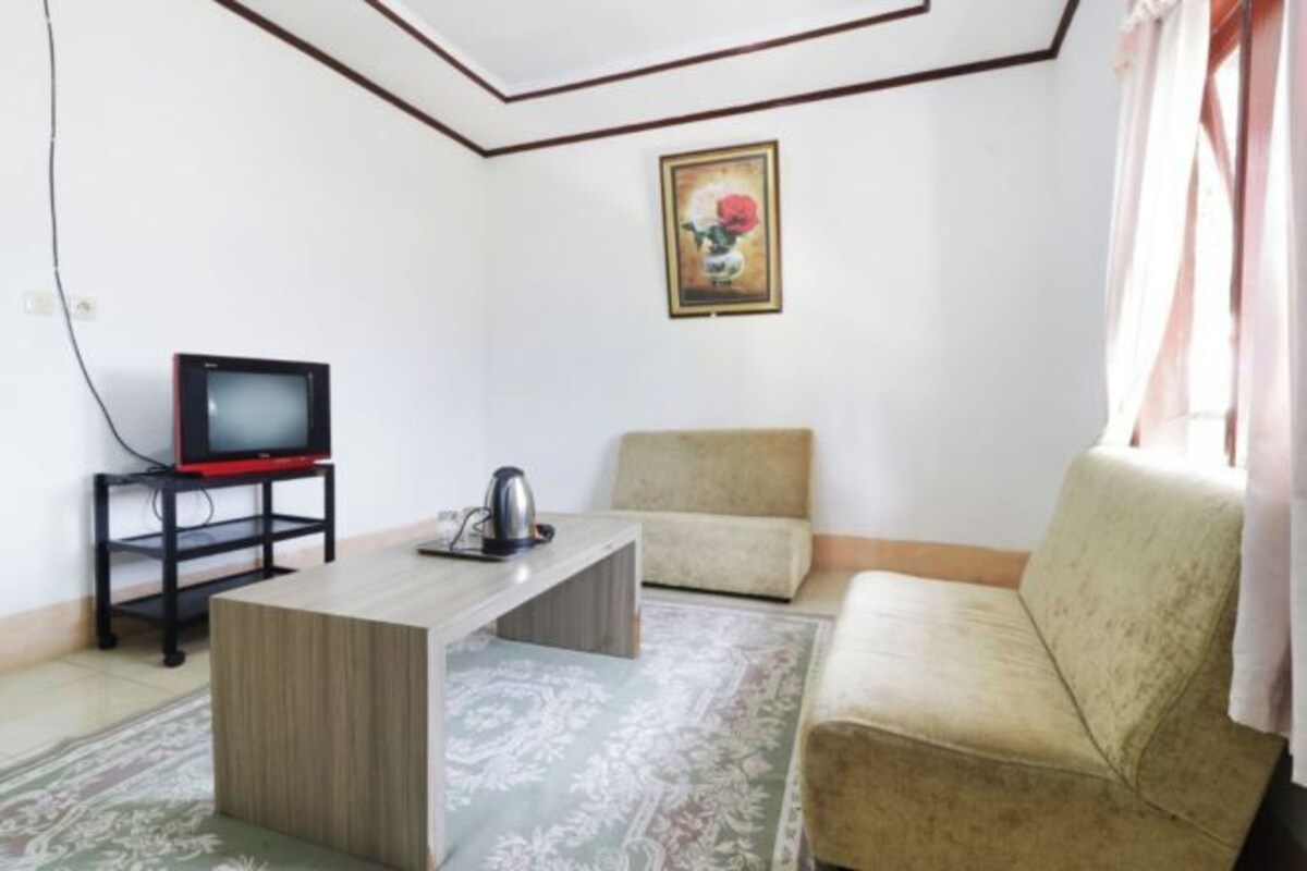 A living room with a sofa, a coffee table, a television on a stand, and a painting on the wall.