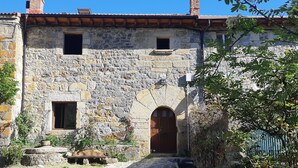 Un bâtiment en pierre avec une porte en bois et deux fenêtres.